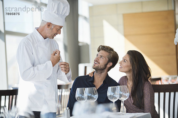 Chefkoch im Gespräch mit einem Paar im Restaurant
