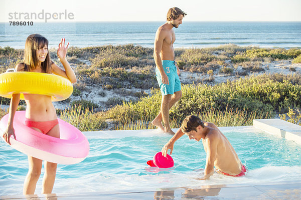 Drei Freunde  die sich an einem Swimmingpool am Strand vergnügen.