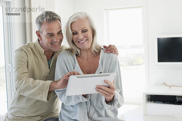Lächelndes Seniorenpaar mit einem digitalen Tablett
