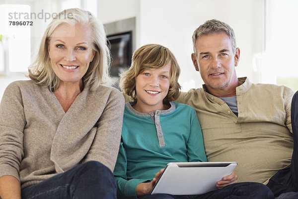 Porträt eines Jungen mit einer digitalen Tafel  der mit seinen Großeltern sitzt.