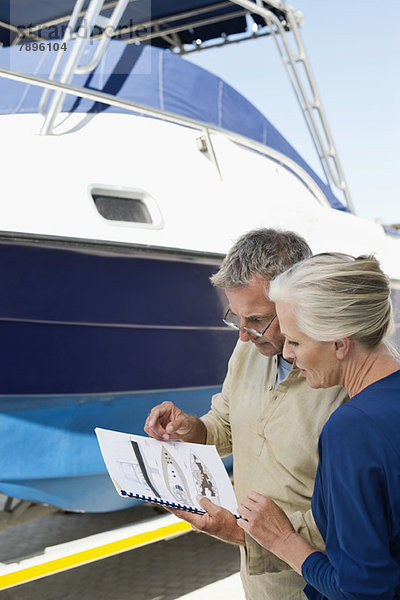 Paar beim Lesen einer Broschüre in der Nähe einer Yacht