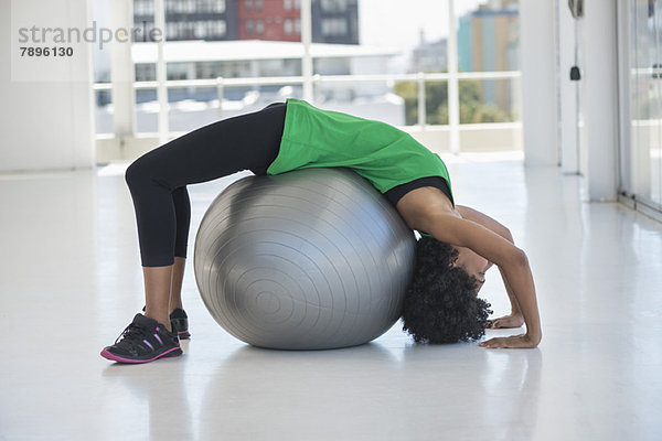 Frau beim Training auf einem Fitnessball im Fitnessstudio