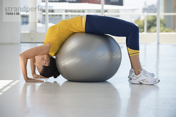 Frau beim Training auf einem Fitnessball im Fitnessstudio