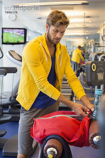 Mann  der seine Tasche nach dem Training in einem Fitnessstudio packt.