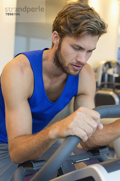 Mann beim Training an einer Maschine im Fitnessstudio