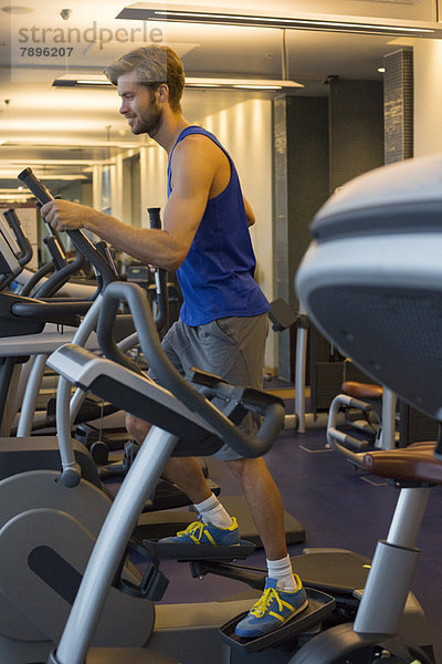 Mann beim Training an einer Maschine im Fitnessstudio