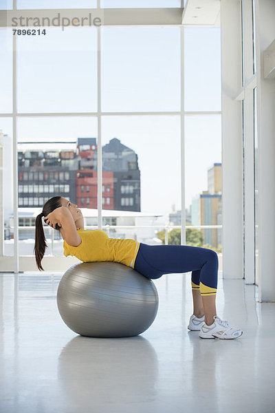 Frau beim Training auf einem Fitnessball im Fitnessstudio