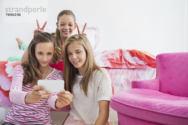 Drei Mädchen beim Fotografieren mit dem Handy auf einer Pyjamaparty