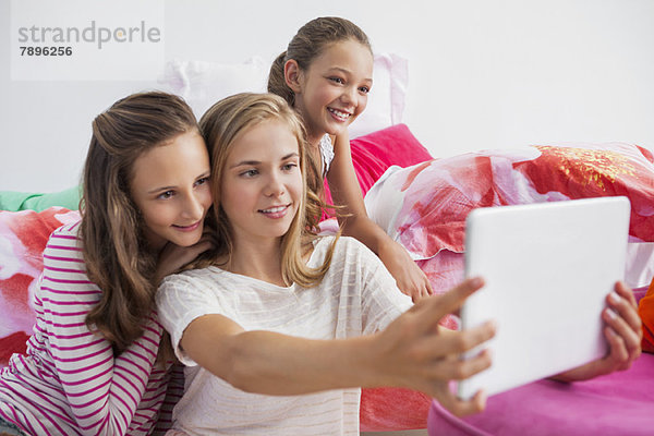 Drei Mädchen mit einem digitalen Tablett auf einer Pyjamaparty