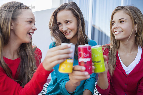 Nahaufnahme von drei Mädchen  die mit Getränkedosen anstoßen