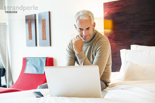 Mann mit Laptop im Hotelzimmer