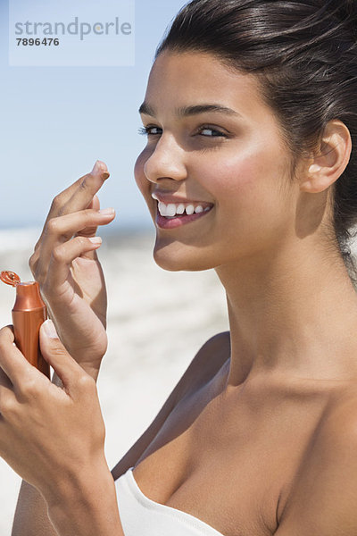 Schöne Frau riecht Sonnencreme am Strand