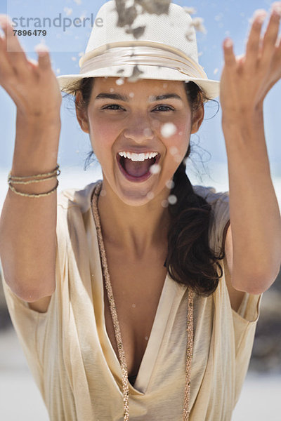 Frau spielt mit Sand am Strand