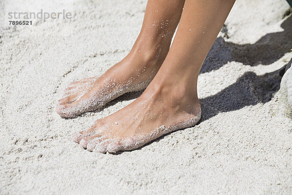 Frauenfüße im Sand am Strand