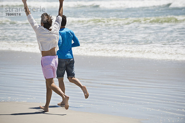 Zwei Männer  die am Strand rennen.