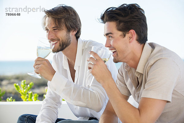 Zwei männliche Freunde genießen Weißwein im Freien