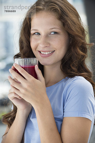 Lächelnde Frau mit einem Glas Granatapfelsaft