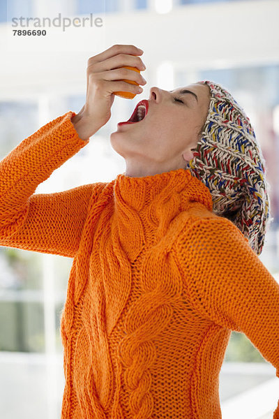 Frau drückt Saft aus einer Orange in den Mund