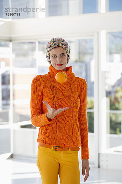 Porträt einer Frau  die eine Orange wirft