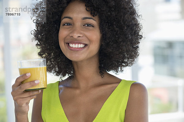 Porträt einer lächelnden Frau mit einem Glas Mango-Shake