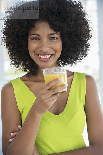 Porträt einer lächelnden Frau mit einem Glas Mango-Shake