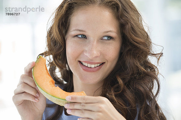 Nahaufnahme einer lächelnden Frau beim Melonenessen