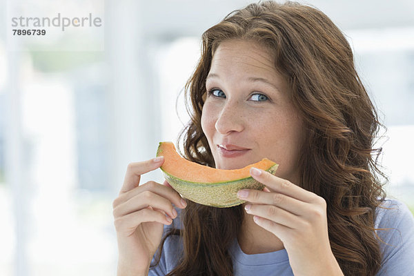 Porträt einer lächelnden Frau beim Melonenessen