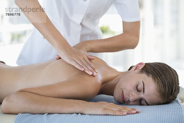 Frau erhält Rückenmassage von einem Massagetherapeuten