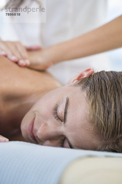 Frau erhält Rückenmassage von einem Massagetherapeuten