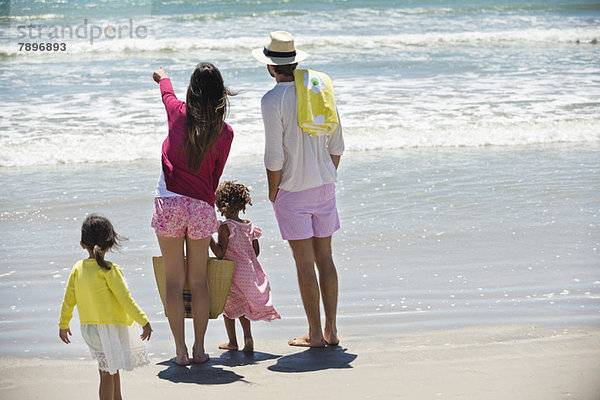 Kinder mit ihren Eltern beim Blick aufs Meer am Strand