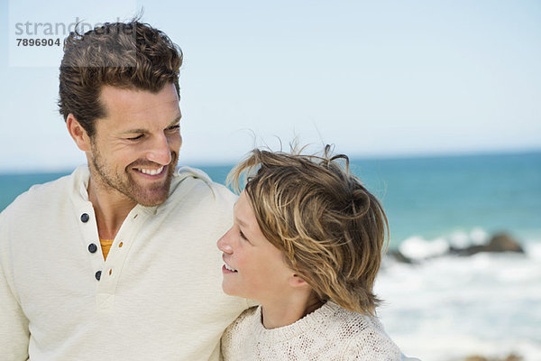 Mann mit seinem Sohn lächelnd am Strand
