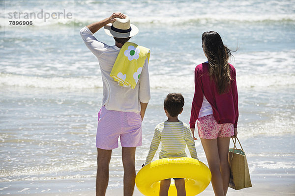 Junge mit seinen Eltern auf das Meer am Strand blickend