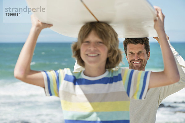 Mann und Sohn mit Surfbrett am Strand