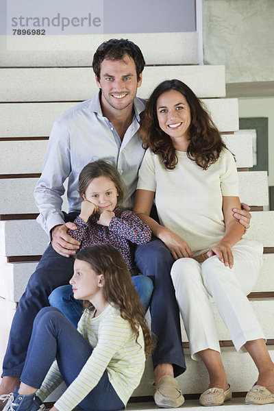 Paar mit ihren Kindern auf einer Treppe sitzend