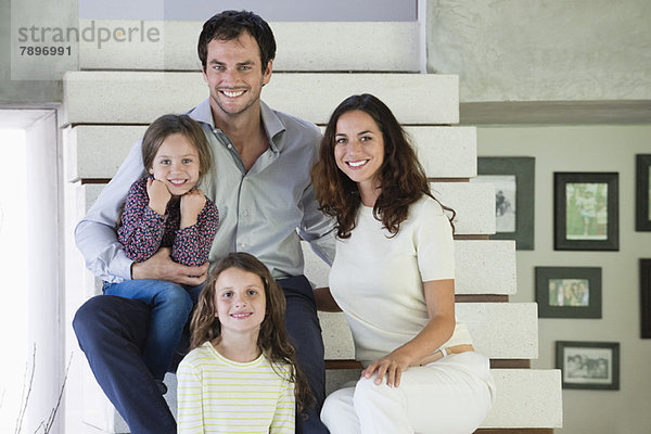 Familie sitzt auf der Treppe und lächelt