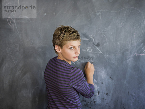 Junge schreibt an einer Tafel im Klassenzimmer