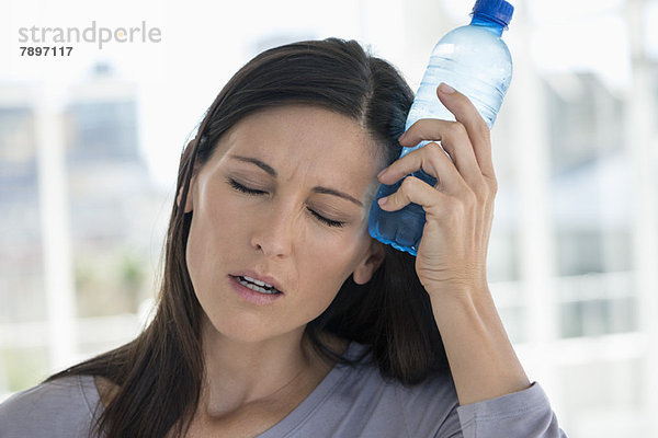 Frau mit einer Wasserflasche auf der Stirn