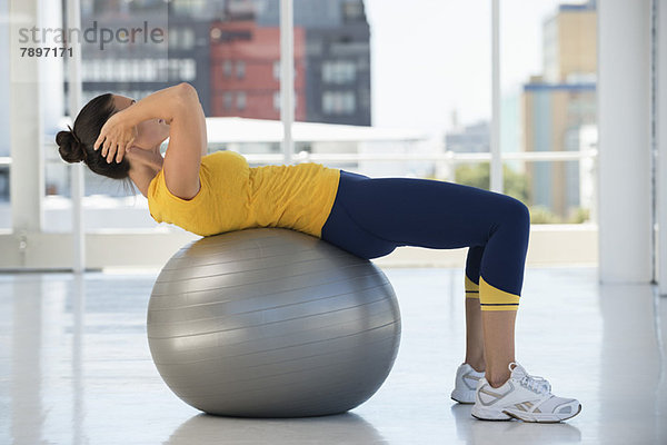 Frau beim Training auf einem Fitnessball im Fitnessstudio