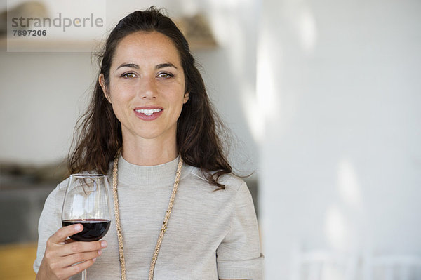 Porträt einer Frau  die ein Weinglas hält und lächelt
