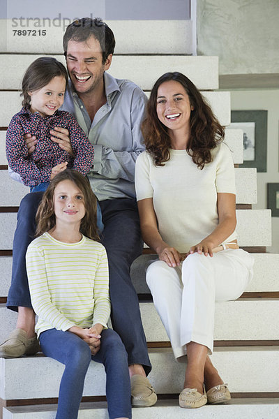 Familie sitzt auf der Treppe und lächelt