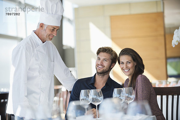 Chefkoch im Gespräch mit einem Paar im Restaurant