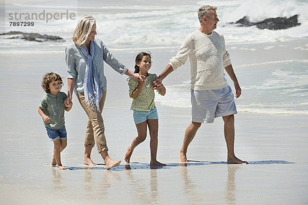 Kinder  die mit ihren Großeltern am Strand spazieren gehen
