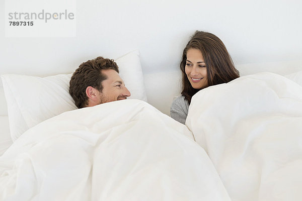 Lächelndes Paar auf dem Bett liegend