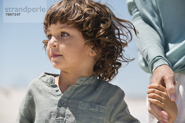 Junge mit der Hand seiner Großmutter am Strand