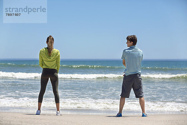 Rückansicht einer Frau und ihres Trainers beim Training am Strand
