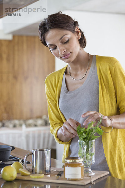 Frau beim Zubereiten von Kräutertee in der Küche