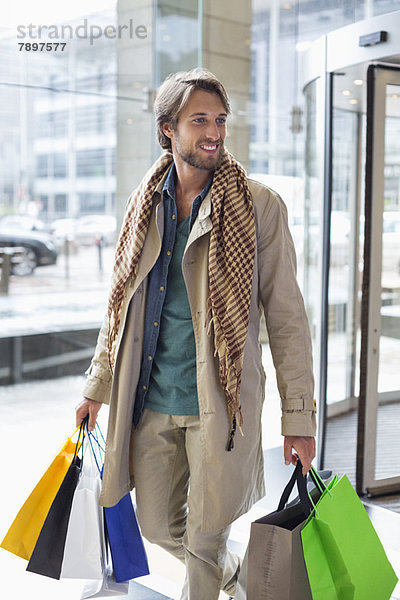 Mann trägt Einkaufstaschen und lächelt