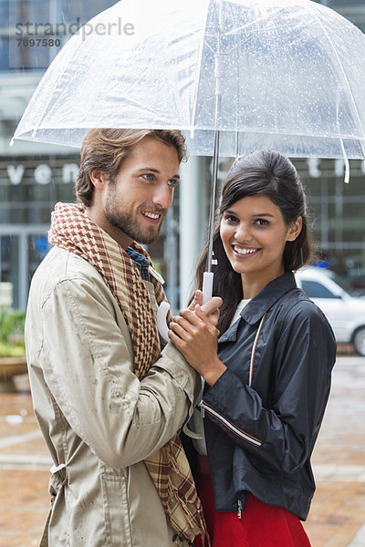 Lächelndes Paar unter einem Schirm