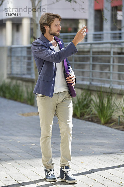 Mann beim Fotografieren mit dem Handy auf der Straße