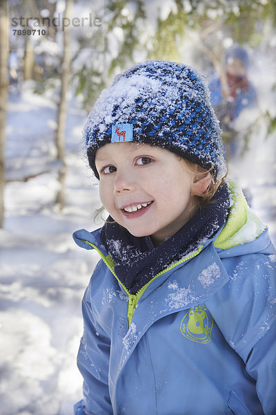 Junge in Winterkleidung mit verschneiter Mütze